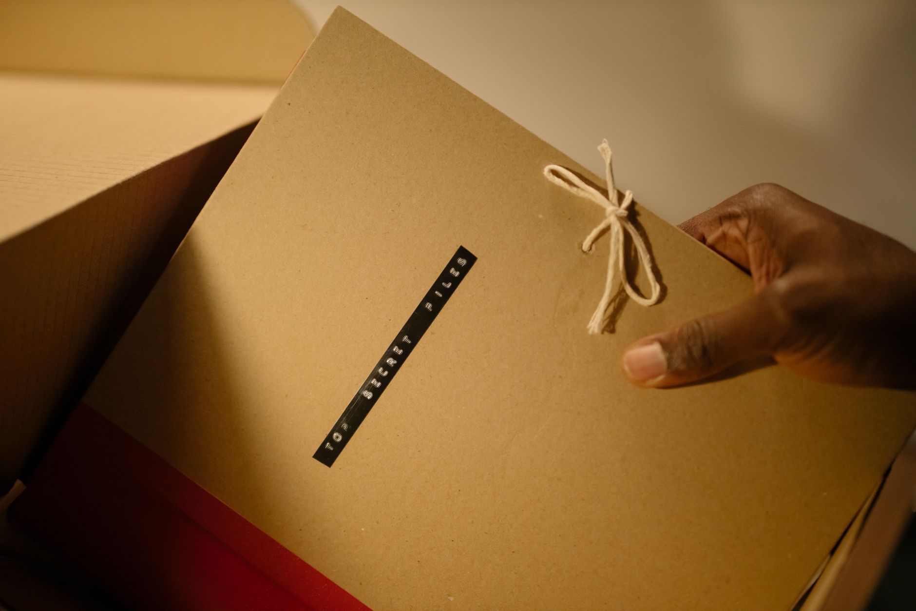 Close-up of hand holding top secret document folder in a box.