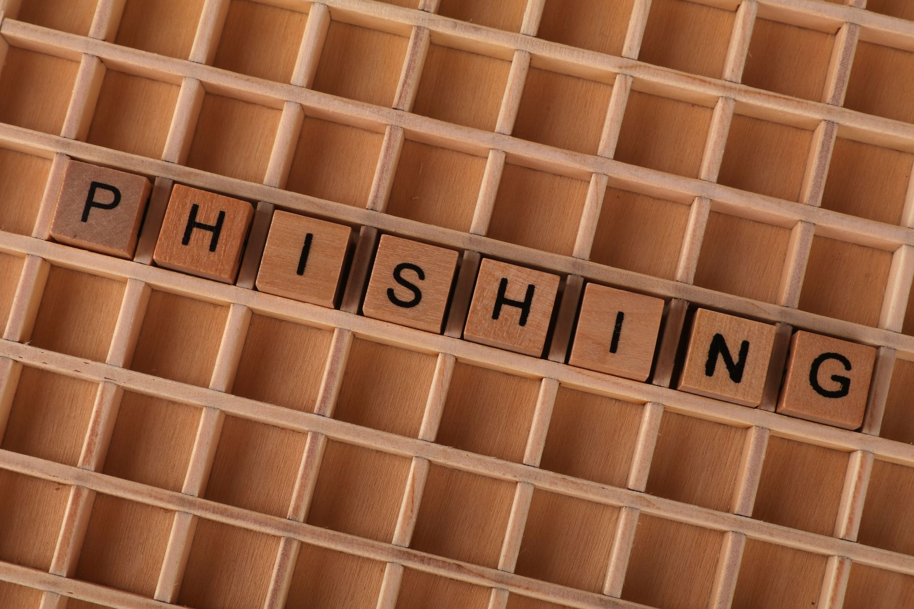 High-angle view of wooden letter tiles spelling 'Phishing', representing online security threats.