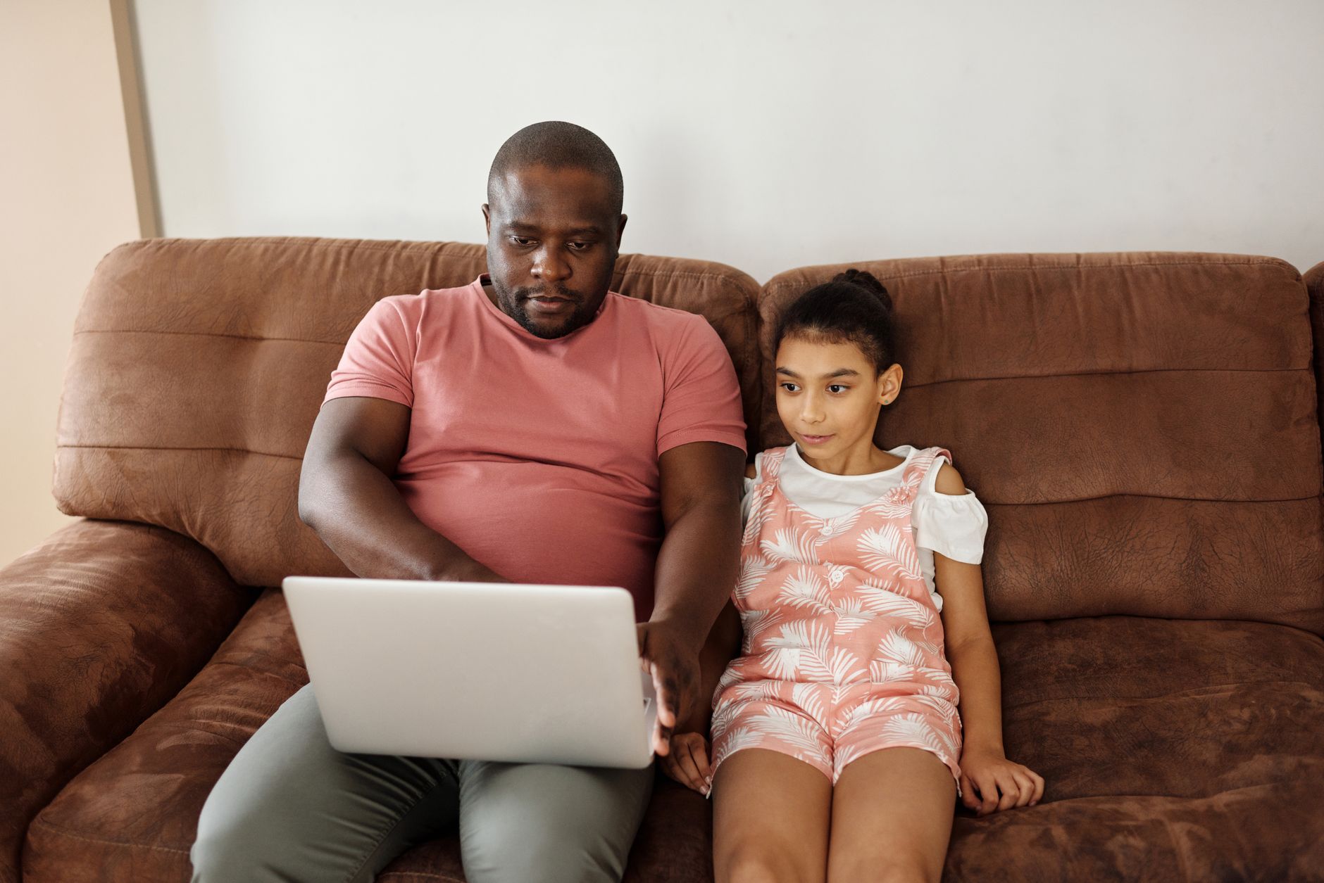 Father and daughter spending quality time together on the sofa using a laptop.