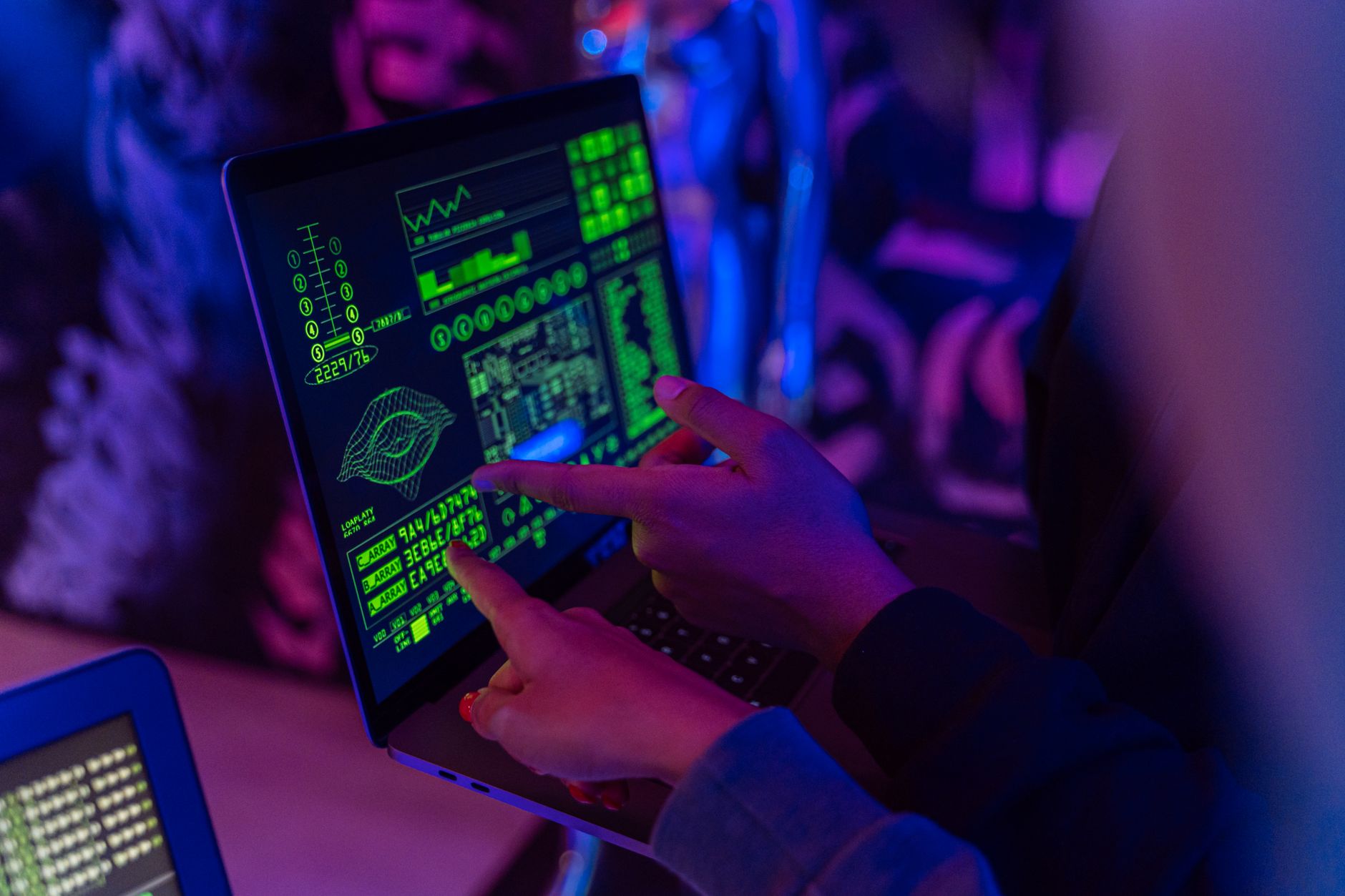 A person analyzing cybersecurity data on a laptop in a dimly lit room.