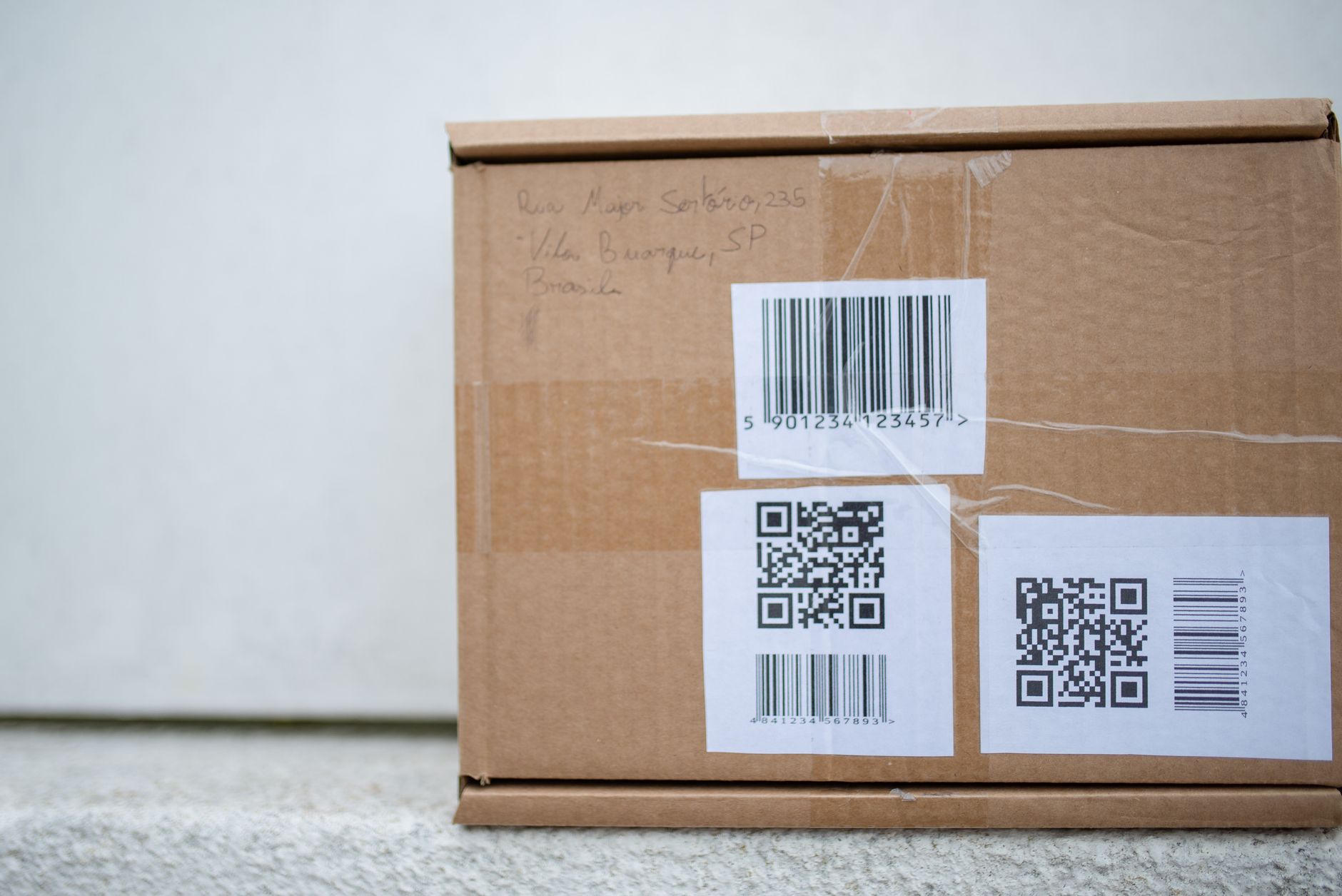 Close-up of a cardboard package with QR codes and a barcode, ideal for delivery and shipping concepts.