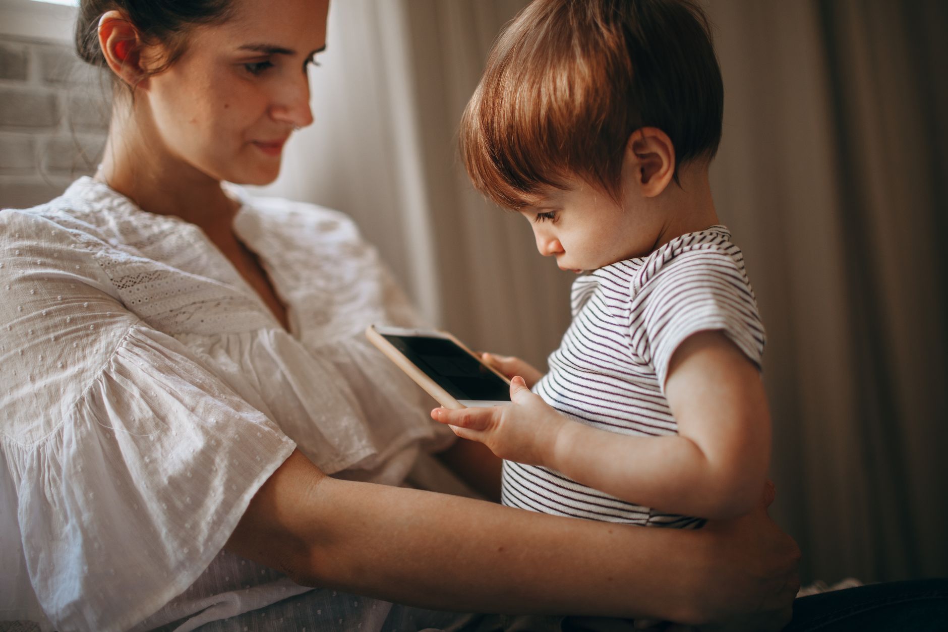 A tender moment between mother and child as they explore a smartphone together, enjoying family time.