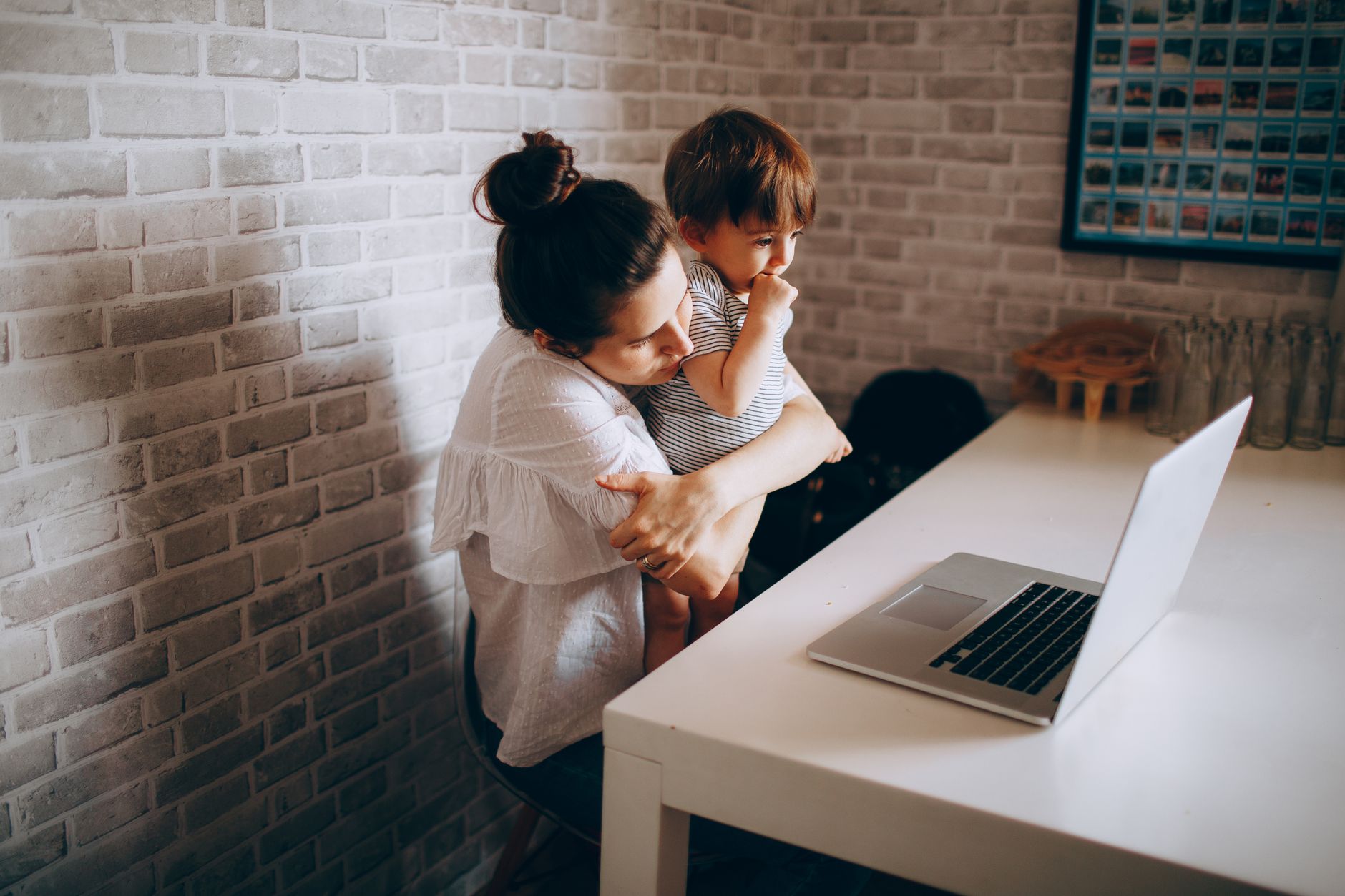 A mother and her child engage in a video call using a laptop, creating a warm family moment at home.